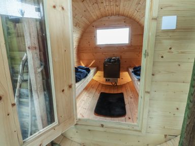 A sauna with wooden benches and heating unit at The Journeyman Luxury Shepherds Hut in Barnoldswick