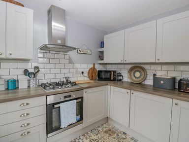 A kitchen with white cabinets a gas stove an oven a microwave toaster and various kitchen utensils at Phocle Ridge in Phocle Green near Ross-On-Wye
