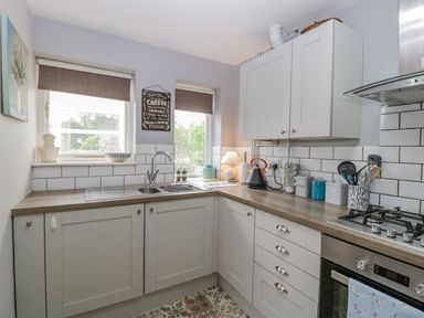 A kitchen with white cabinets a double sink gas stove and kitchen utensils at Phocle Ridge in Phocle Green near Ross-On-Wye