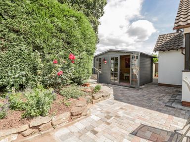 A garden area with a flower bed and a wooden shed with open doors at Phocle Ridge in Phocle Green near Ross-On-Wye