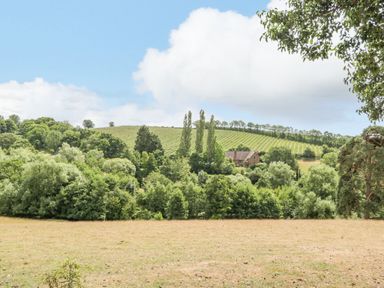 A countryside landscape with trees hills a field and a house at Phocle Ridge in Phocle Green near Ross-On-Wye