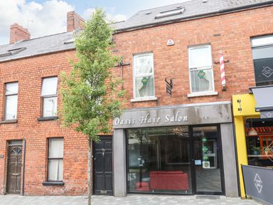 A brick building with a hair salon and a tree in front at The Upper Room in Ballymena