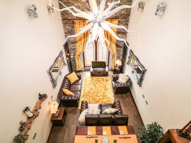 A living room with leather sofas yellow cushions a yellow rug and large windows at The Upper Room in Ballymena