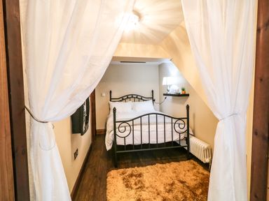 A bedroom with a metal bed frame a rug a lamp and white curtains at The Upper Room in Ballymena