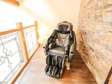 A massage chair next to a glass railing and a stone wall at The Upper Room in Ballymena