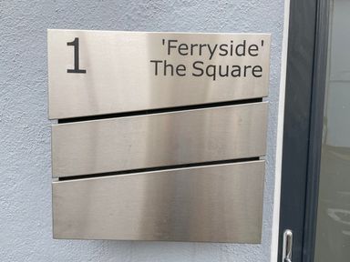 A metal sign on a wall showing number 1 and Ferryside The Square with two empty panels