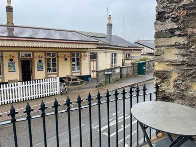 A street view with a wooden building featuring posters a white picket fence and a picnic bench at Ferryside in Kingswear