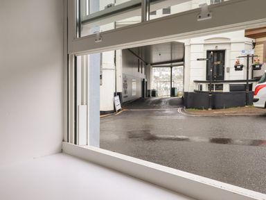 A street view through a window opening showing a covered walkway and building entrance at Ferryside in Kingswear