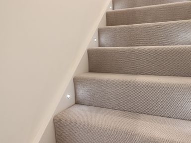 Carpeted stairs with small recessed wall lights at Ferryside in Kingswear