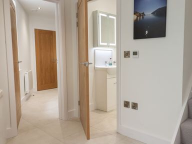 A hallway with wooden doors and a partially open door showing a bathroom sink at Ferryside in Kingswear