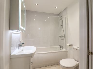A bathroom with a bathtub shower combination and a toilet at Ferryside in Kingswear