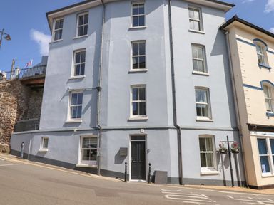 A blue building with white window frames and a black door on a street corner at Ferryside in Kingswear