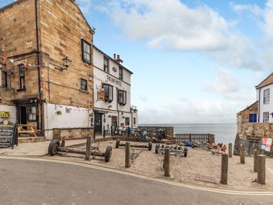 A cobblestone street leading to the sea with The Bay Hotel and stone buildings at The Shepherds Rest in Robin Hoods Bay