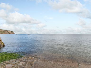 A coastal view with a rocky shore and calm sea with boats in the distance at The Shepherd's Rest in Robin Hood's Bay