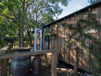 A wooden deck with barrels flowers and a telescope outside a wooden cabin at The Shepherds Rest in Robin Hoods Bay