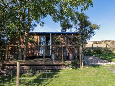 A wooden cabin with a small porch and garden fencing in a rural setting at The Shepherd's Rest in Robin Hood's Bay