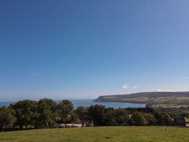A coastal landscape with green fields trees and hills by the sea at The Shepherd's Rest in Robin Hood's Bay