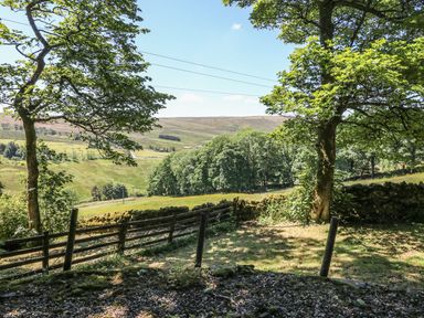 A landscape view with trees a wooden fence and stone wall overlooking hills at Keepers in Nenthead near Alston