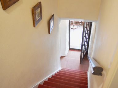 A staircase with red carpet leading to a doorway with a wooden framed glass door at Keepers in Nenthead near Alston