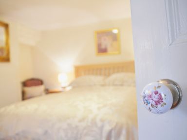 A bedroom with a bed a chair a lamp and framed pictures at Keepers in Nenthead near Alston