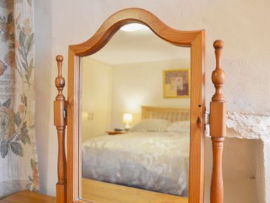 A wooden framed mirror reflecting a bedroom with a bed lamp and a picture on the wall at Keepers in Nenthead near Alston