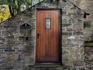 A wooden door set in a stone wall with a sign reading The Bothy at Bothy Nenthall near Alston