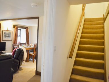 A carpeted staircase with wooden handrails next to a dining area with a table set for a meal at Chestnut in Nenthall near Alston