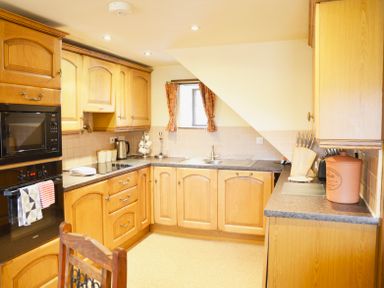 A kitchen with wooden cabinets a sink a countertop oven microwave and kitchen utensils at Chestnut in Nenthall near Alston
