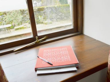 A wooden window sill with a pen and red book labeled guests near a window at Chestnut in Nenthall near Alston