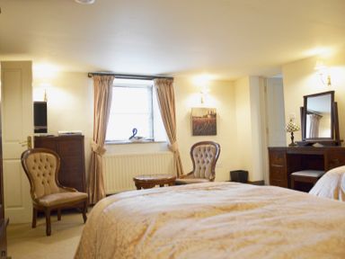 A bedroom with two antique chairs a wooden dressing table and a chest of drawers at Chestnut in Nenthall near Alston