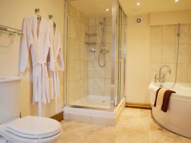 A bathroom with a shower enclosure bathtub bathrobes and a toilet at Chestnut in Nenthall near Alston