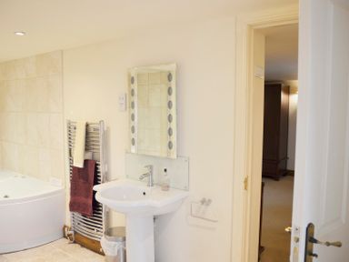 A bathroom with a sink pedestal mirror and towel rack next to a bathtub at Chestnut in Nenthall near Alston