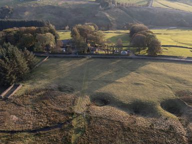 An aerial view of fields with trees houses and a stone wall at Chestnut in Nenthall near Alston