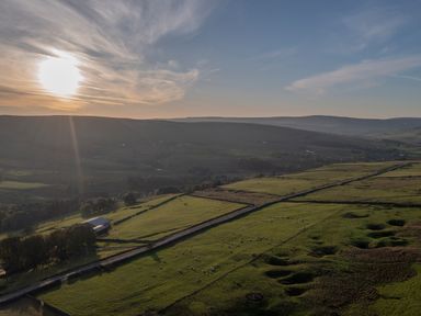 A rural landscape with fields separated by stone walls a barn and hills in the background at Chestnut in Nenthall near Alston