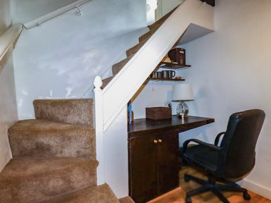 A home office area with a desk and chair under the staircase at Vi’s Valley View Pentewan