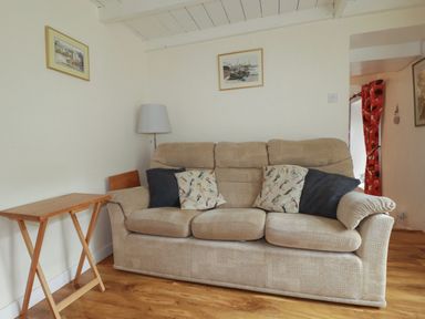 A living room with a sofa and a side table at Vi’s Valley View Pentewan
