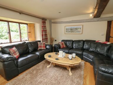 A living room with black leather sofas and a wooden coffee table at Penarth in Cregrina near Builth Wells