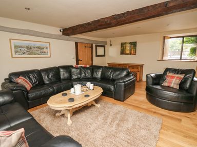 A living room with black leather sofas a wooden coffee table and a rug at Penarth in Cregrina near Builth Wells