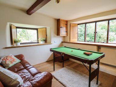 A room with a pool table a brown leather sofa and windows with wooden shutters at Penarth in Cregrina near Builth Wells