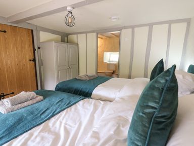 A bedroom with two single beds a wardrobe and a view into a bathroom at Penarth Cregrina near Builth Wells