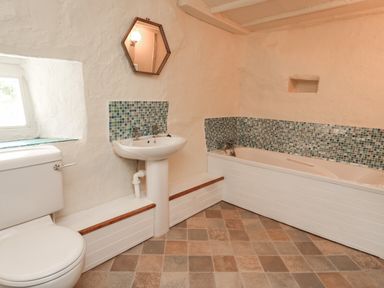 A bathroom with a toilet sink bathtub tiled floor and mosaic wall tiles at Penarth in Cregrina near Builth Wells