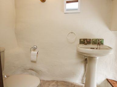 A small bathroom with a toilet and a pedestal sink with floral tiles at Penarth in Cregrina near Builth Wells