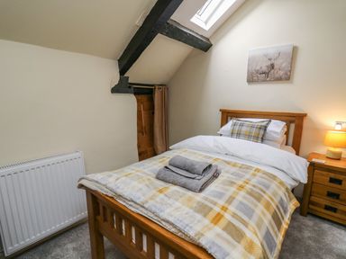 A bedroom with a wooden bed and nightstand with a lamp at Penarth in Cregrina near Builth Wells