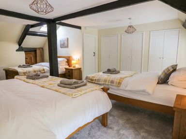 A bedroom with three single beds with folded towels and blankets and wooden furniture at Penarth Cregrina near Builth Wells
