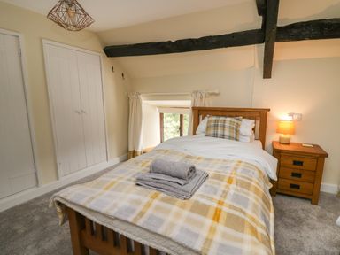 A bedroom with a wooden bed and bedside table with lamp at Penarth in Cregrina near Builth Wells
