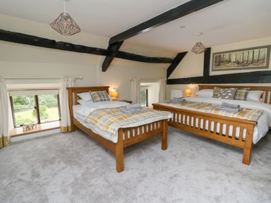 A bedroom with two wooden beds gray carpet and small windows at Penarth in Cregrina near Builth Wells