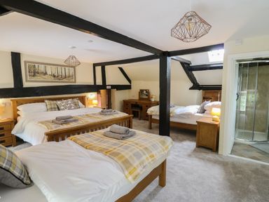 A bedroom with multiple beds wooden furniture and exposed black beams at Penarth in Cregrina near Builth Wells
