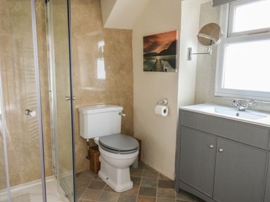 A bathroom with a shower enclosure a toilet a sink with cabinet and a window at Penarth Cregrina near Builth Wells