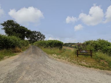 A gravel road beside a metal gate and sign reading Penarth in a rural area at Penarth in Cregrina near Builth Wells