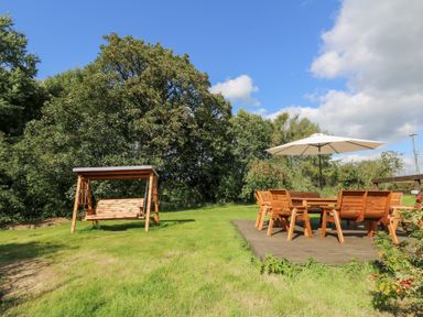 A garden with a swing and seating area at Penarth in Cregrina near Builth Wells